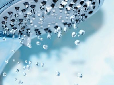 closeup-of-a-shower-head-with-sprinkling-water-blue-toned-photo